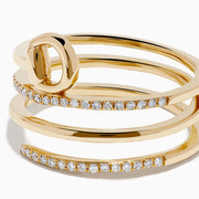 The D'Oro 14K Yellow Gold Spiral Diamond Ring features three bands, two adorned with sparkling diamonds. The top band forms a graceful circular loop, offering an elegant and modern touch.