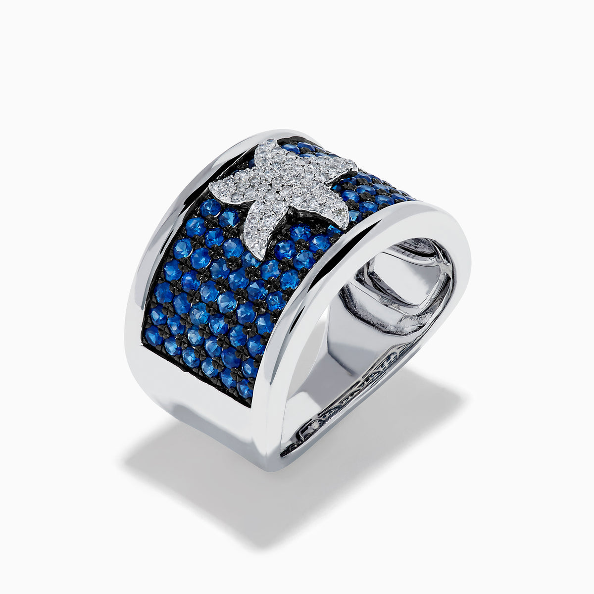 The Sterling Silver Blue Sapphire and Diamond Starfish Ring features a white starfish with clear crystals set among round blue sapphires atop a wide, curved band for a unique and stylish look.