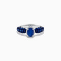 The 14K White Gold Blue Sapphire and Diamond Ring showcases a striking oval blue sapphire center, surrounded by sparkling diamonds, with additional sapphires set along the band.