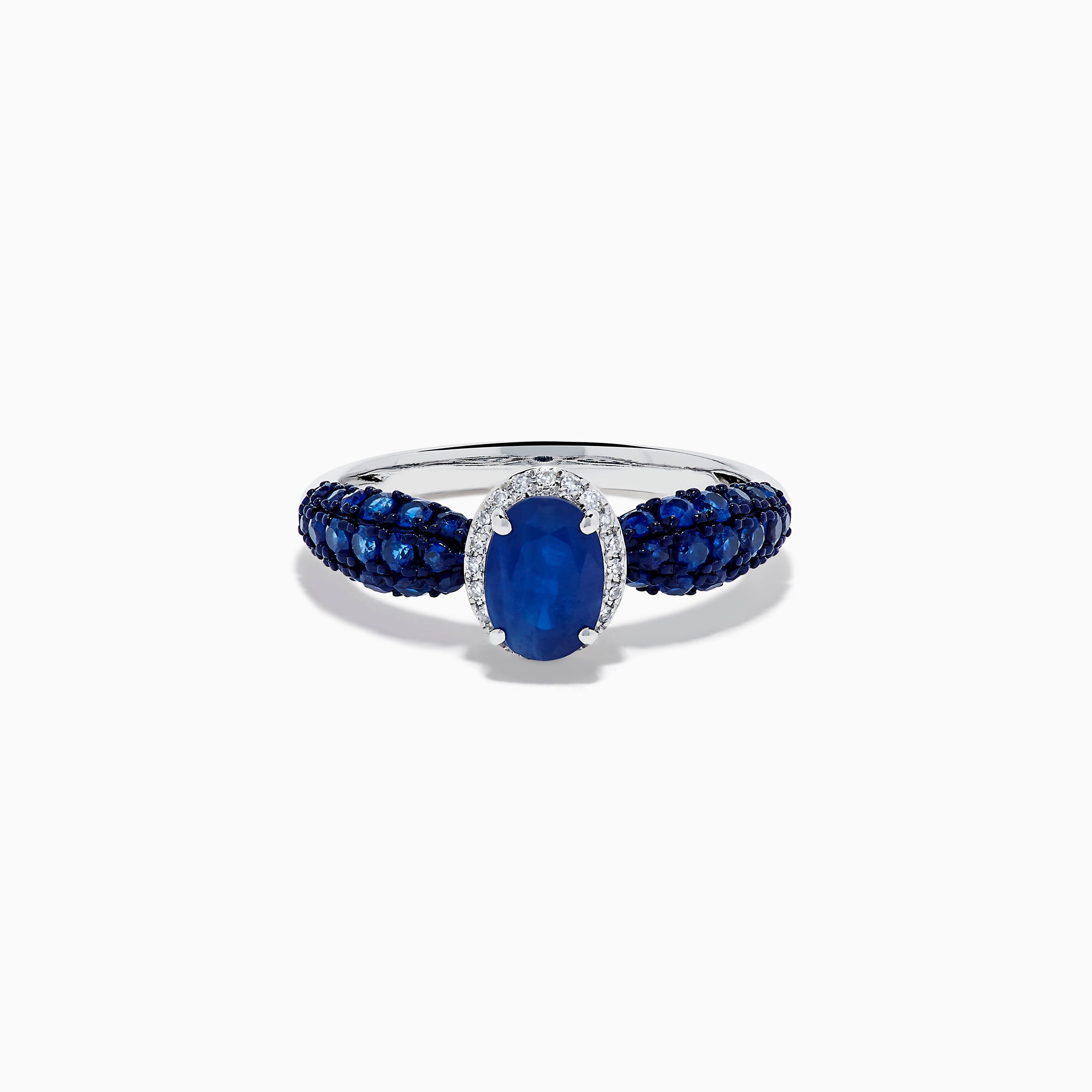 The 14K White Gold Blue Sapphire and Diamond Ring showcases a striking oval blue sapphire center, surrounded by sparkling diamonds, with additional sapphires set along the band.