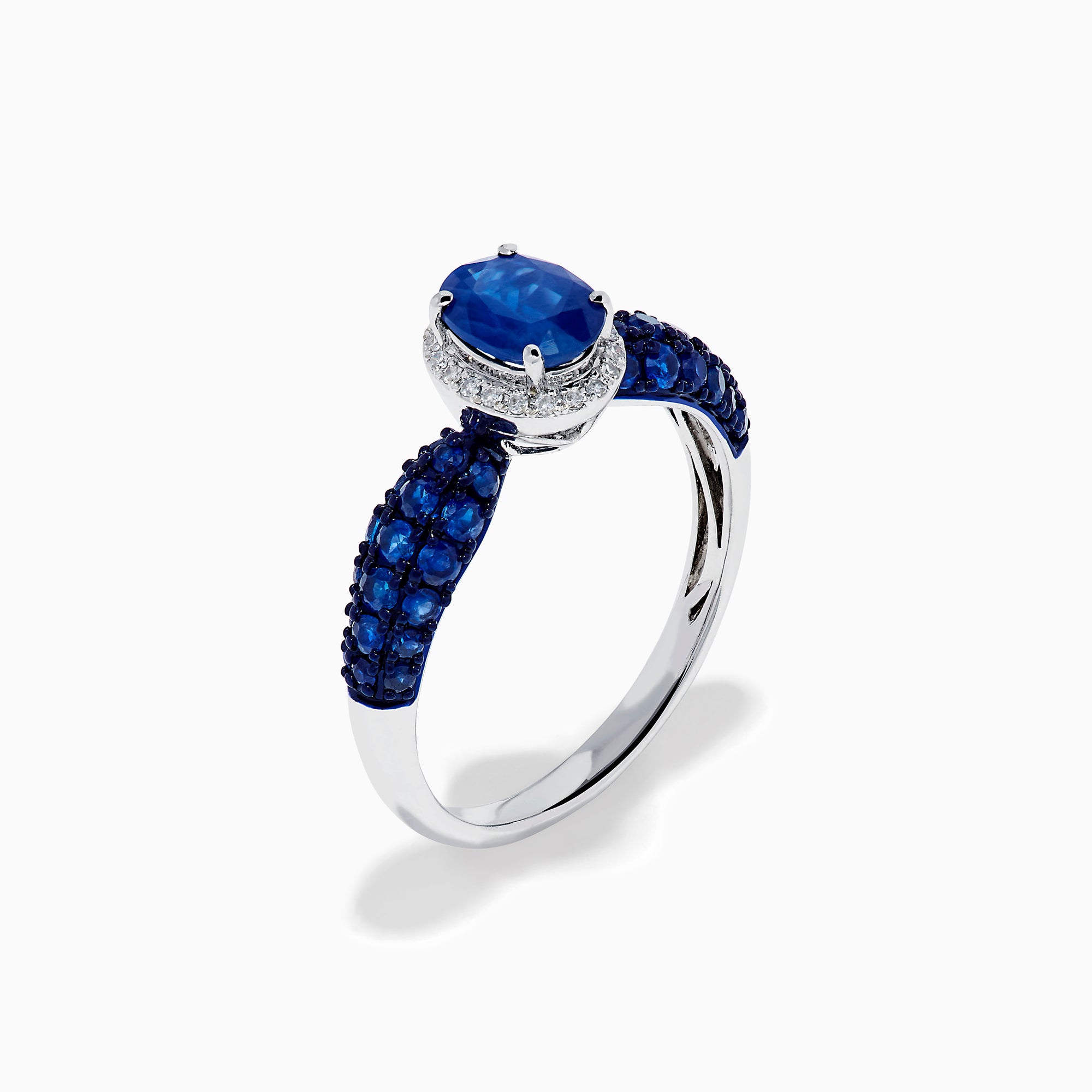 The 14K White Gold Blue Sapphire and Diamond Ring showcases a striking oval blue sapphire center, surrounded by sparkling diamonds, with additional sapphires set along the band.