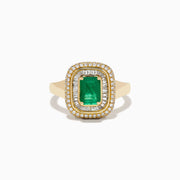 The 14K Yellow Gold Emerald and Diamond Double Halo Ring features an emerald-cut green gemstone at the center, framed by two rows of round and baguette diamonds in a rectangular halo setting.