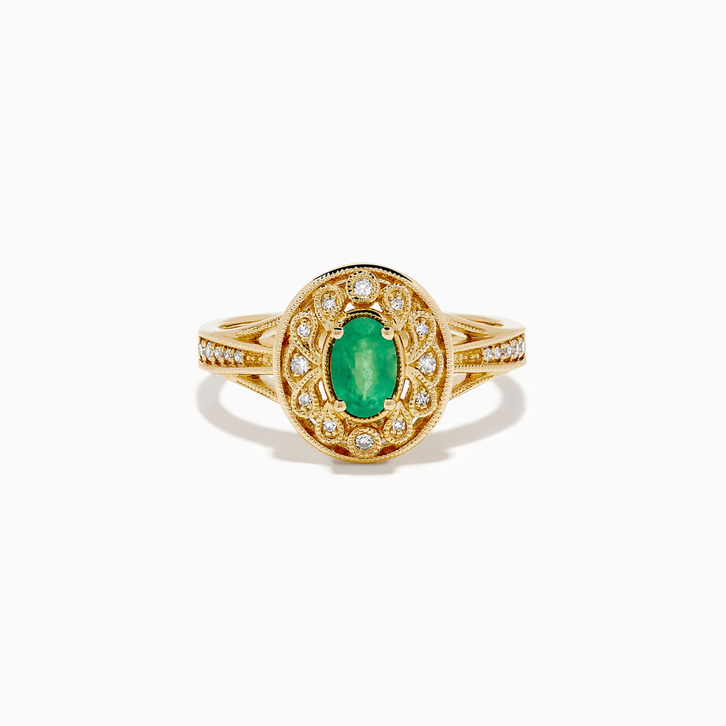 The 14K Yellow Gold Emerald and Diamond Filigree Halo Ring showcases a central oval green emerald, surrounded by a sparkling diamond halo and diamonds set along the split band.