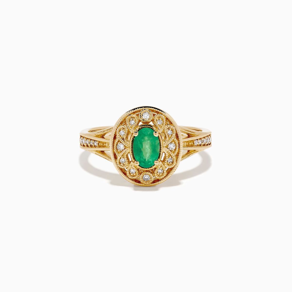The 14K Yellow Gold Emerald and Diamond Filigree Halo Ring showcases a central oval green emerald, surrounded by a sparkling diamond halo and diamonds set along the split band.