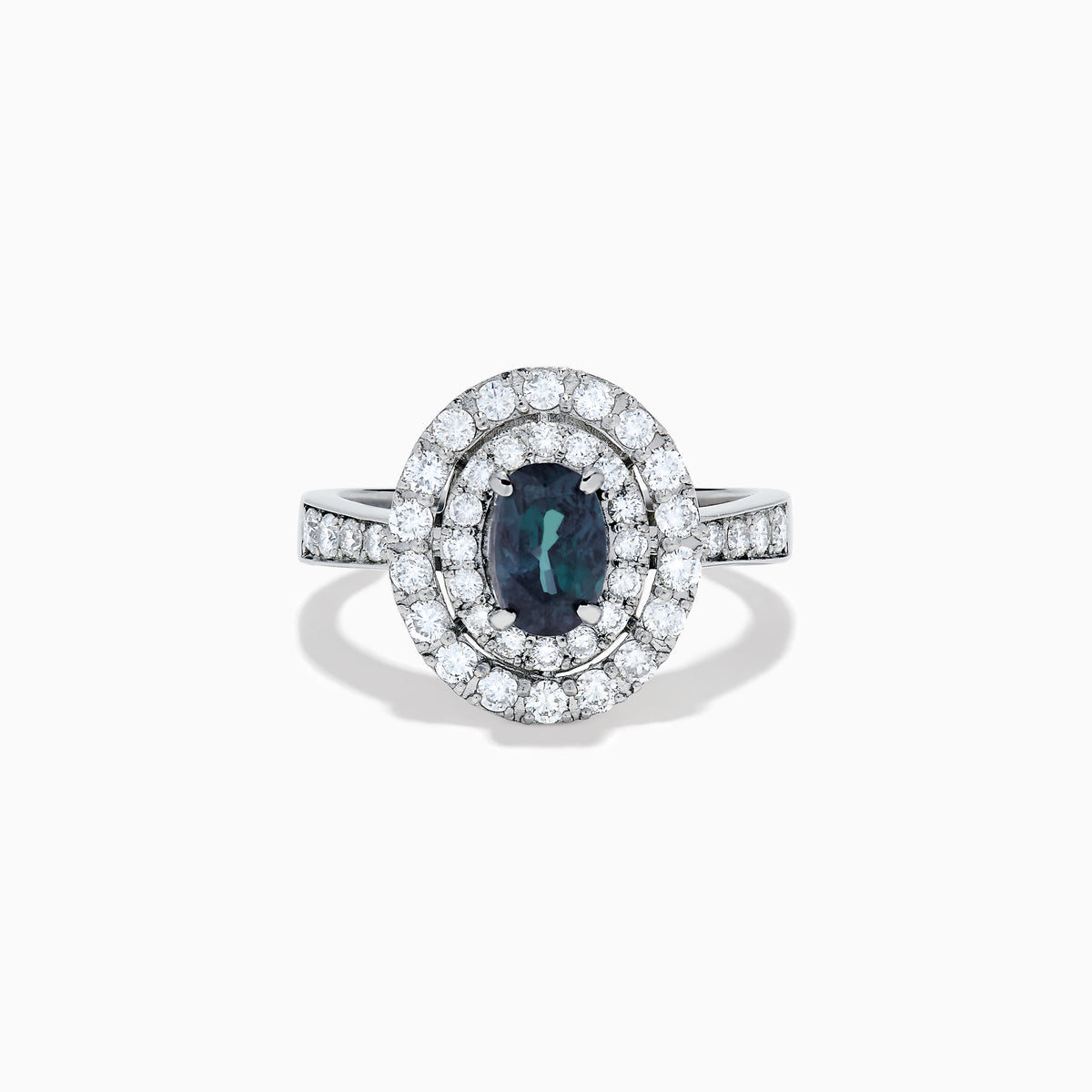 The Platinum GIA Certified Alexandrite and Diamond Double Halo Ring showcases an oval dark blue Alexandrite center stone, two rows of sparkling round diamonds in a double halo, and additional diamonds on the band, all set against a white background.