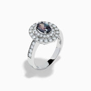 The Platinum GIA Certified Alexandrite and Diamond Double Halo Ring showcases an oval dark blue Alexandrite center stone, two rows of sparkling round diamonds in a double halo, and additional diamonds on the band, all set against a white background.
