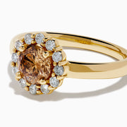 The 14K Yellow Gold Brown and White Diamond Halo Ring features a round brown and white diamond center, accented by a halo of sparkling small white diamonds.