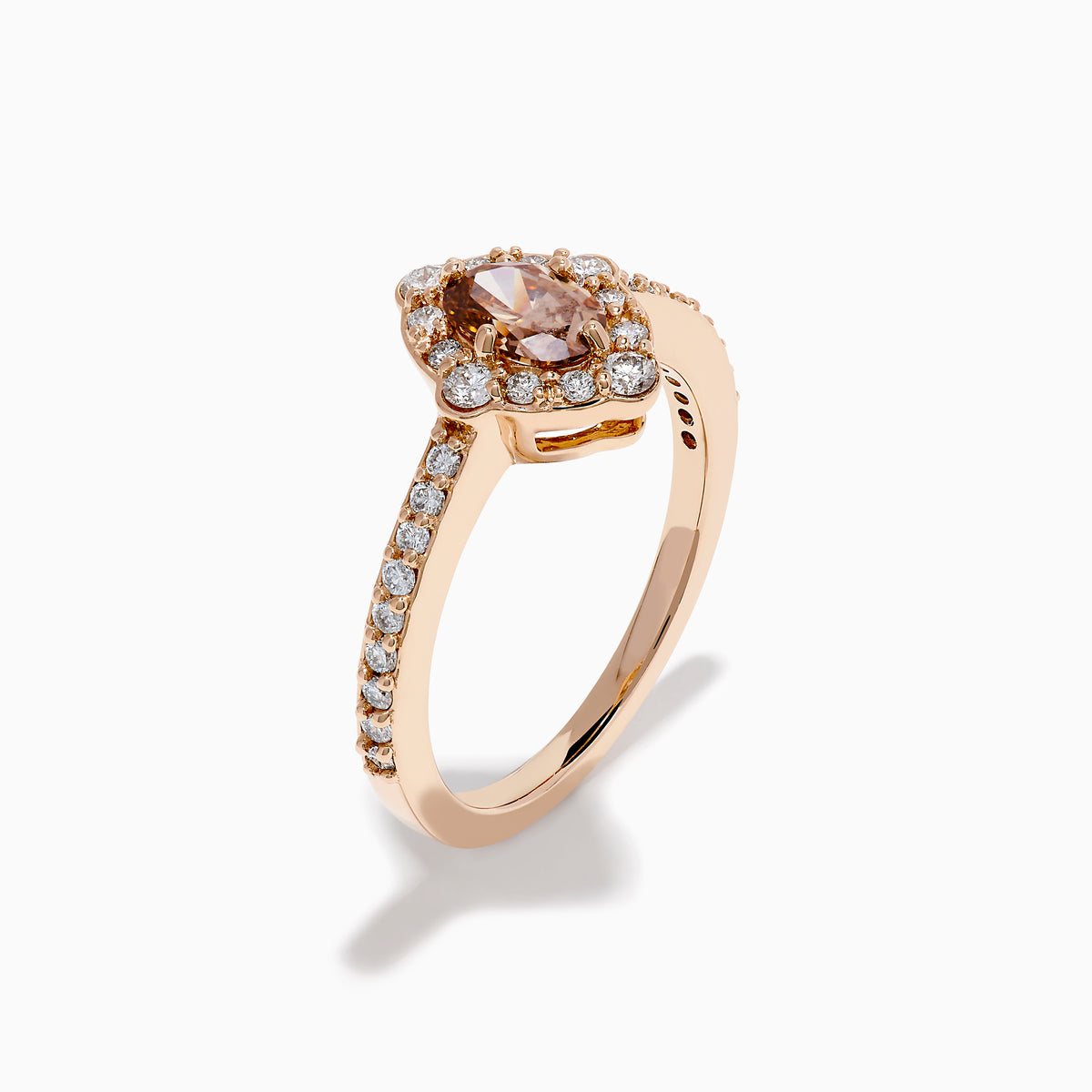 The 14K Rose Gold Brown and White Diamond Halo Ring showcases an oval brown and white diamond center, encircled by a halo of white diamonds and set with additional diamonds along the band.