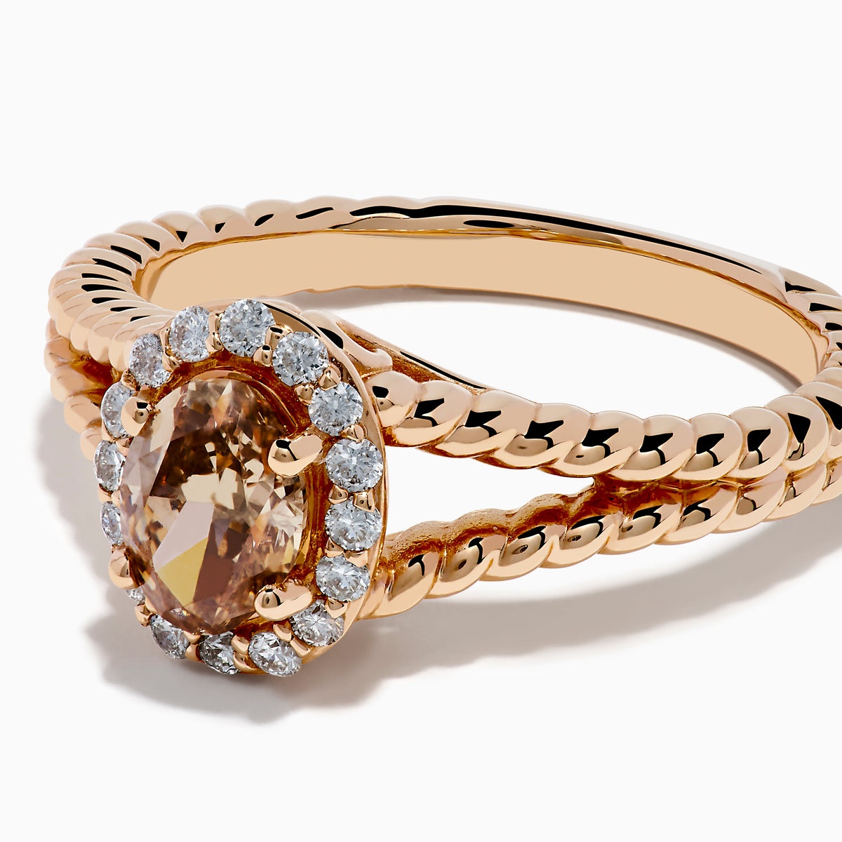 The Espresso 14K Rose Gold Brown Diamond Ring features an oval light brown diamond surrounded by a halo of small white diamonds and set on a twisted rose gold band.