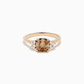 The 14K Rose Gold Cushion Cut Brown and White Diamond Ring features a central cushion-cut brown and white diamond with three small white diamonds on each side, all set in rose gold against a white background.