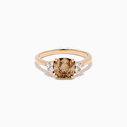 The 14K Rose Gold Cushion Cut Brown and White Diamond Ring features a central cushion-cut brown and white diamond with three small white diamonds on each side, all set in rose gold against a white background.