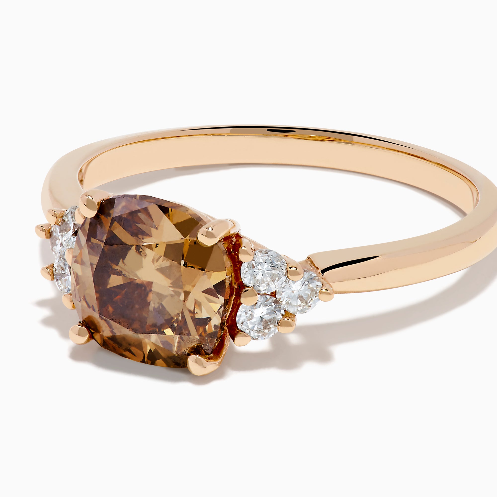 The 14K Rose Gold Cushion Cut Brown and White Diamond Ring features a central cushion-cut brown and white diamond with three small white diamonds on each side, all set in rose gold against a white background.