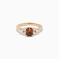 The 14K Rose Gold Brown and White Diamond Ring features a rectangular brown gemstone at the center with three round white diamonds on each side, all set in a simple rose gold band against a white background.