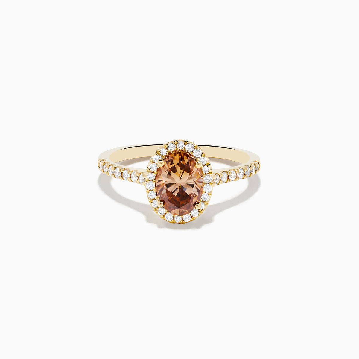The Espresso 14K Yellow Gold Brown Diamond Halo Ring showcases an oval brown diamond center, encircled by a halo of white diamonds with additional diamonds set along the band.