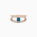 The Bella Bleu 14K Rose Gold Blue and White Diamond Ring features two parallel, diamond-encrusted bands and a cushion-cut blue gemstone centerpiece. This modern, elegant ring stands out beautifully against a crisp white background.