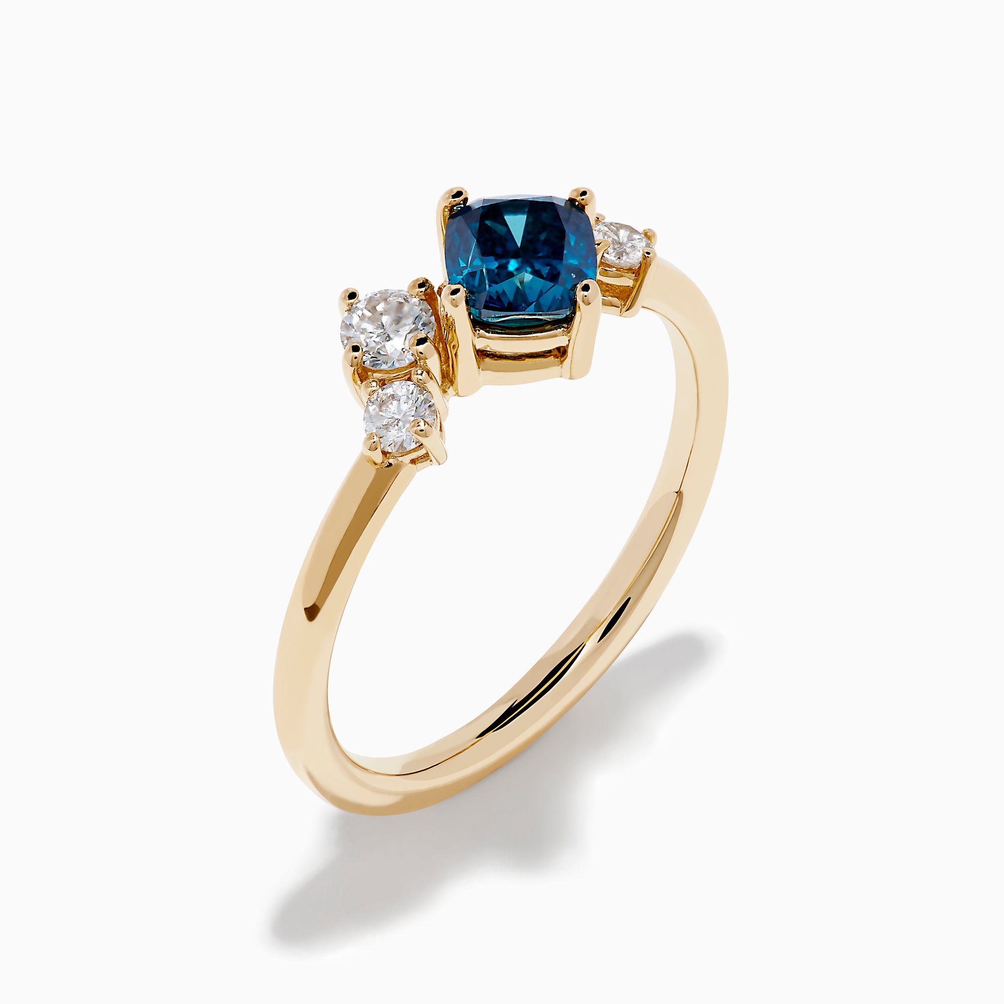 The 14K Yellow Gold Blue and White Diamond Ring showcases a cushion-cut blue stone center with two round white diamonds on each side, set against a white background.