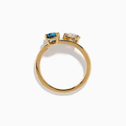 The Bella Bleu 14K Yellow Gold Blue and Light Brown Bypass Diamond Ring showcases an oval white diamond and a cushion-cut deep blue gemstone set side by side on a sleek gold band.