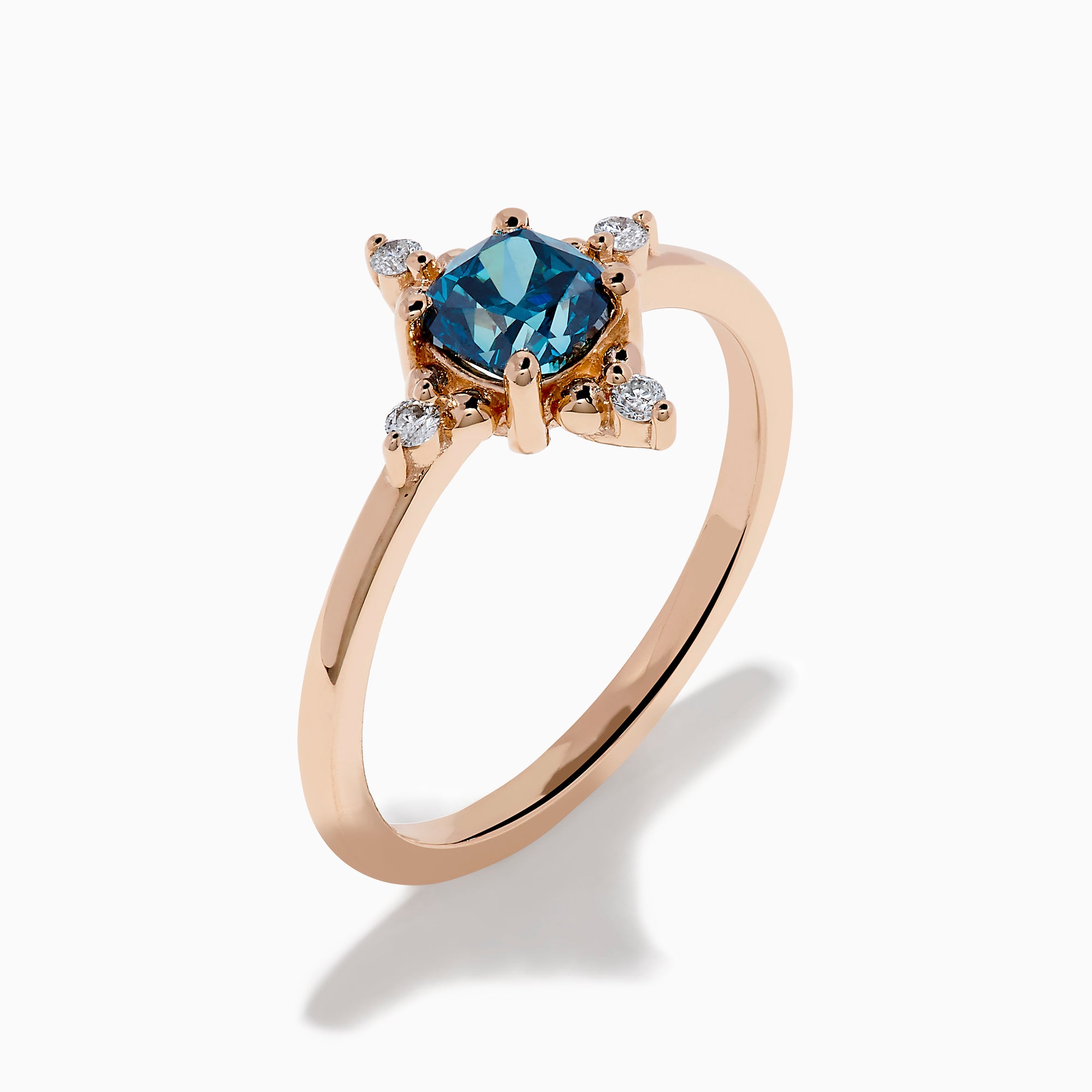 The Bella Bleu 14K Rose Gold Blue and White Diamond Ring features a cushion-cut blue gemstone at its center, accented by four symmetrically placed round white diamonds.