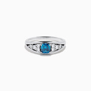The Bella Bleu 14K White Gold Blue and White Diamond Ring showcases a vibrant square-cut blue center stone, accented by rows of round white diamonds on each side, displayed on a white background.