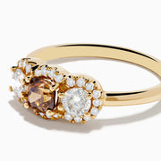 The Espresso 14K Yellow Gold Brown Diamond 3-Stone Ring features a central brown diamond, two oval white stones, and sparkling halo accents for a stunning look.