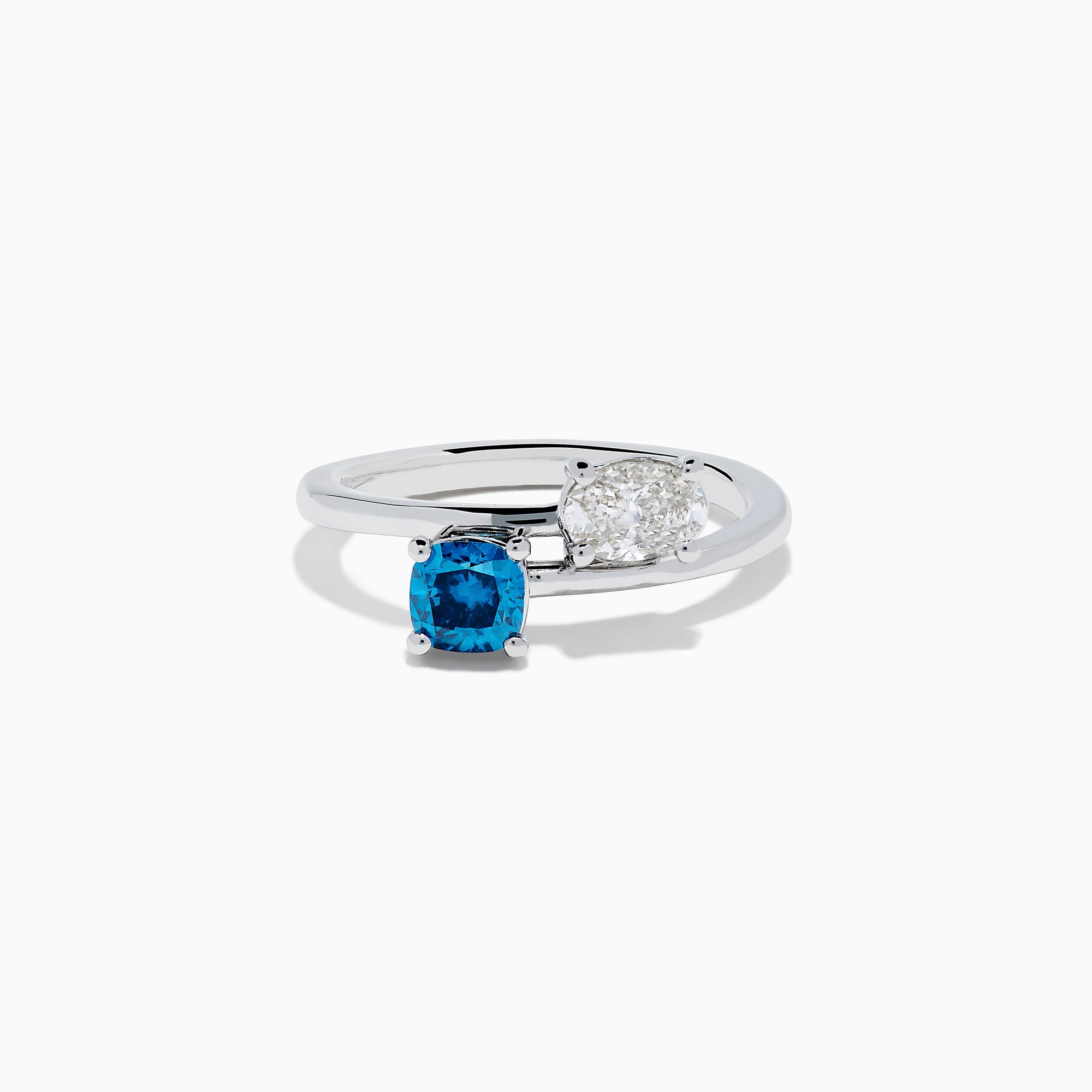 The Bella Bleu 14K White Gold Bypass Ring showcases a blue stone and a light brown diamond set side by side in prongs, displayed against a plain white background.