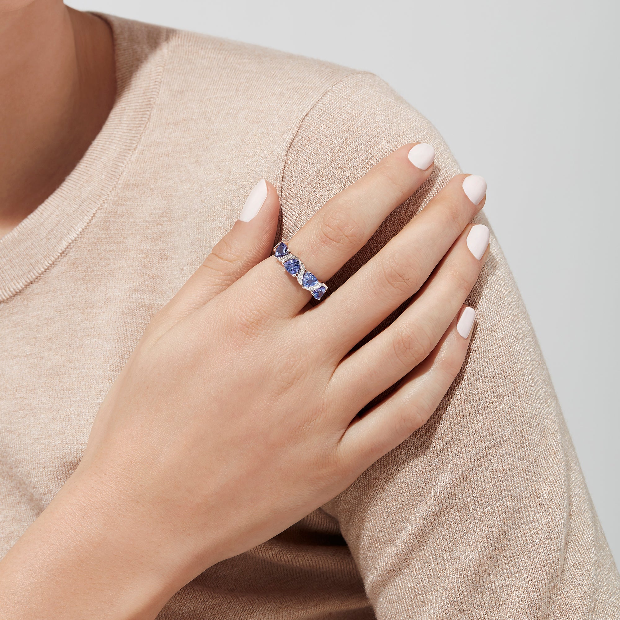 The Nahla Siri 14K White Gold Tanzanite Diamond Ring, 1.58 TCW, features three heart-shaped blue tanzanites set among wavy silver and diamond accents, shown on a white background.