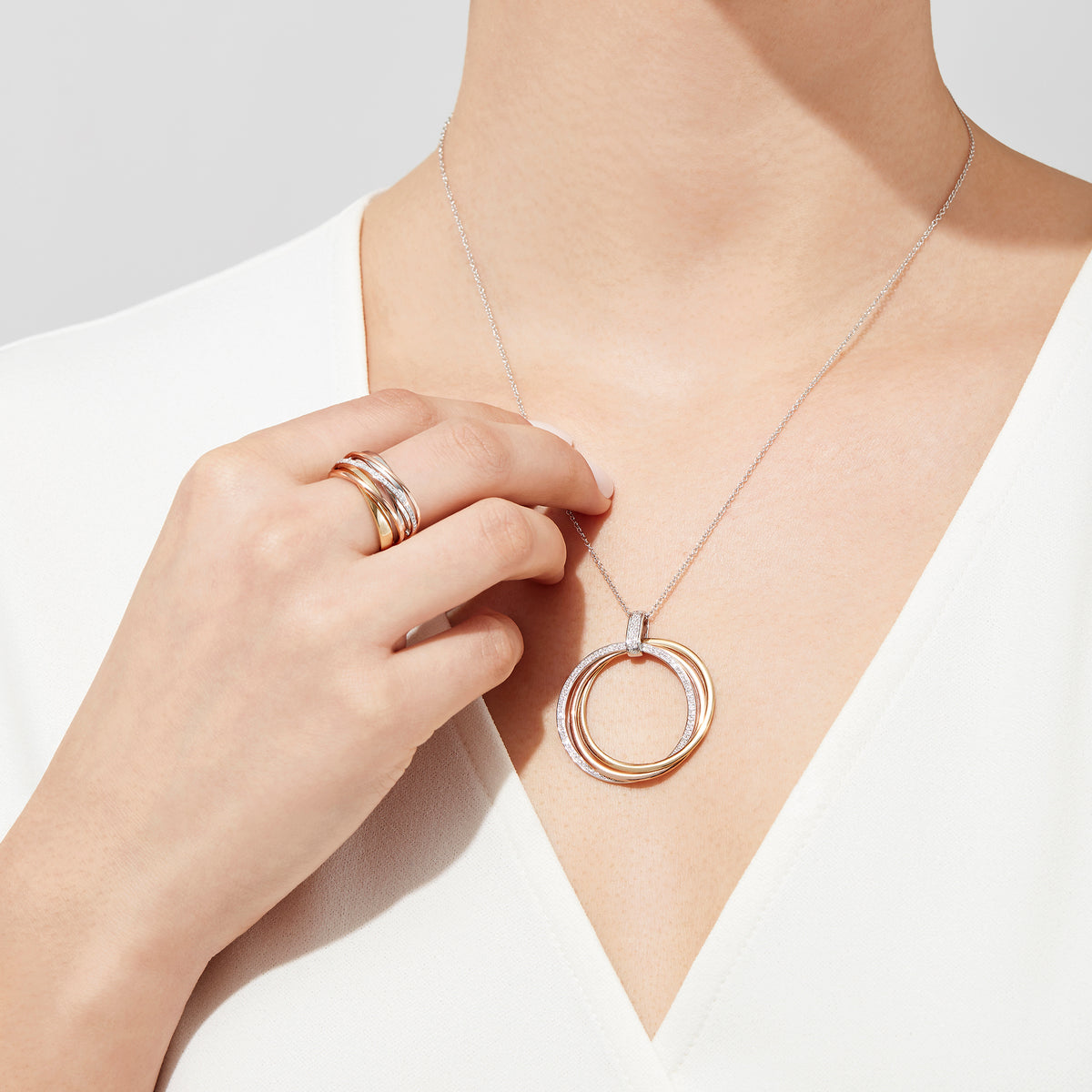 The Trio 14K Tri-Color Gold Diamond Circles Pendant (0.30 TCW) features three interlocking rings in silver, rose, and yellow gold tones with sparkling diamonds, all on a delicate silver chain.