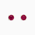 The Ruby Royale 14K Yellow Gold Round Solitaire Ruby Stud Earrings (1.14 TCW) feature faceted rubies in classic four-prong yellow gold settings, showcased on a plain white background.