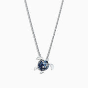 The 925 Sterling Silver Sapphire Splash Turtle Pendant (1.00 TCW) features blue and white gemstones on its shell and is shown against a white background.