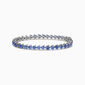 The Nahla Siri Sterling Silver Tanzanite Bracelet, 7.45 TCW, showcases blue triangular gemstones set in prongs and evenly spaced around the band, beautifully displayed against a white background.