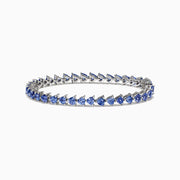 The Nahla Siri Sterling Silver Tanzanite Bracelet, 7.45 TCW, showcases blue triangular gemstones set in prongs and evenly spaced around the band, beautifully displayed against a white background.