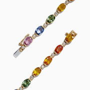 The Watercolors 14K Yellow Gold Sapphire and Diamond Bracelet, 11.20 TCW, features oval sapphires and gemstones in blue, green, yellow, orange, pink, and red evenly spaced around a delicate gold band.