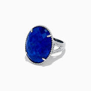 The 925 Sterling Silver Lapis Lazuli Cocktail Ring, 13.85 TCW, features a large faceted oval lapis lazuli gemstone in an ornate prong setting, showcased against a white background.