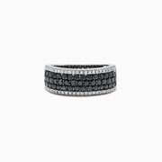 The 14K White Gold Black and White Diamond Ring, 1.28 TCW, features three rows of round black stones in the center, bordered on top and bottom by single rows of sparkling white diamonds.
