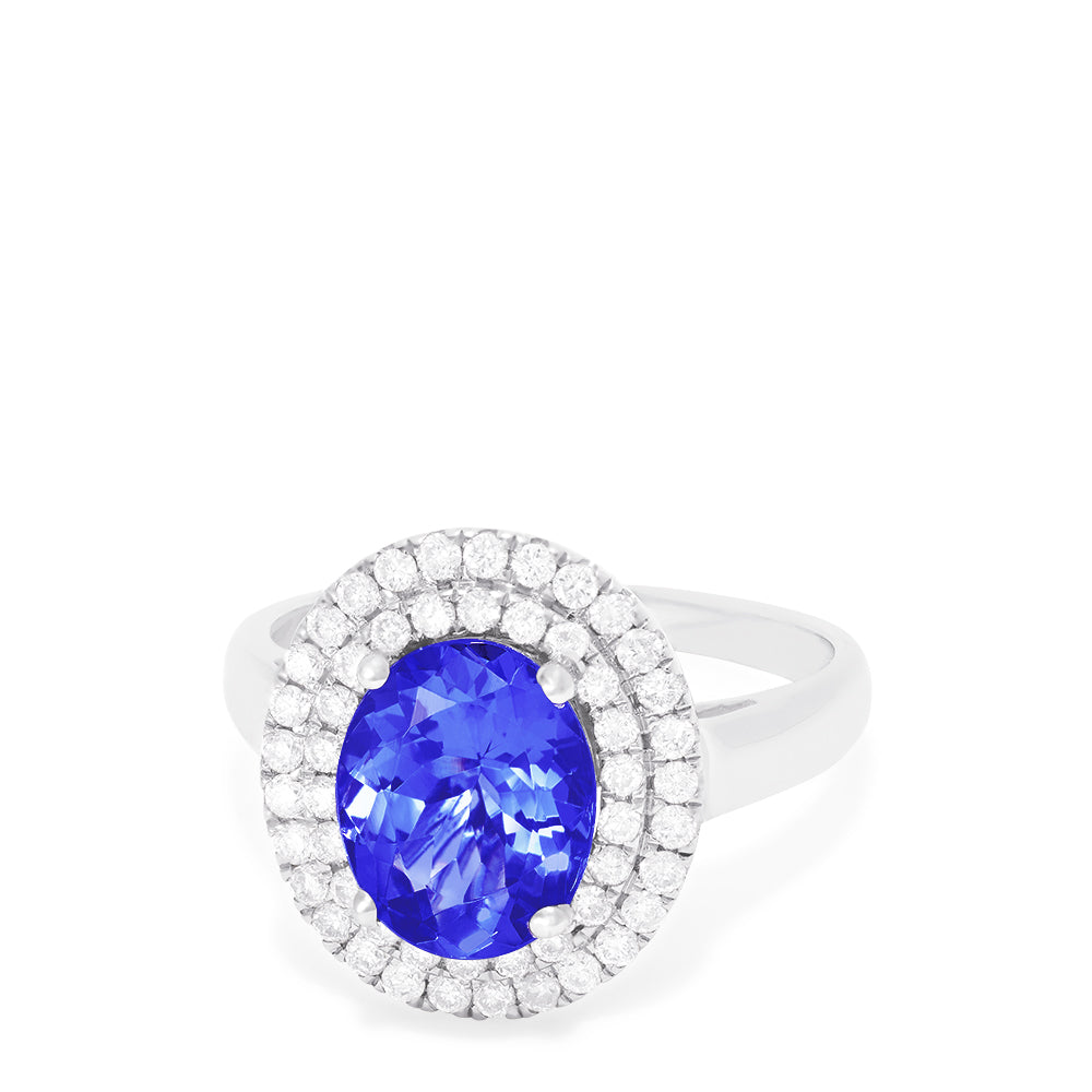 The 14K White Gold Tanzanite and Diamond Ring, 3.13 TCW features a large oval blue tanzanite center stone encircled by two rows of round diamonds in a dazzling halo setting.