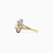 The Aurora 14K Two Tone Gold Opal and Diamond Ring, 1.49 TCW, showcases an oval opal center surrounded by white diamonds on a split-shank band, presented against a white background.