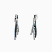 The Bella Bleu 14K White Gold Blue and White Diamond Earrings, 0.58 TCW, feature two intertwined hoops—one adorned with blue and white diamonds—and are displayed against a white background.