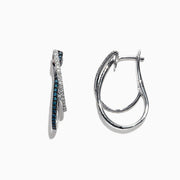 The Bella Bleu 14K White Gold Blue and White Diamond Earrings, 0.58 TCW, feature two intertwined hoops—one adorned with blue and white diamonds—and are displayed against a white background.