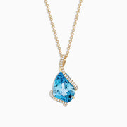 The Ocean Bleu 14K Yellow Gold Pendant features a 6.09 TCW blue topaz framed by sparkling diamonds in an asymmetrical design on a yellow gold chain, set against a white background.