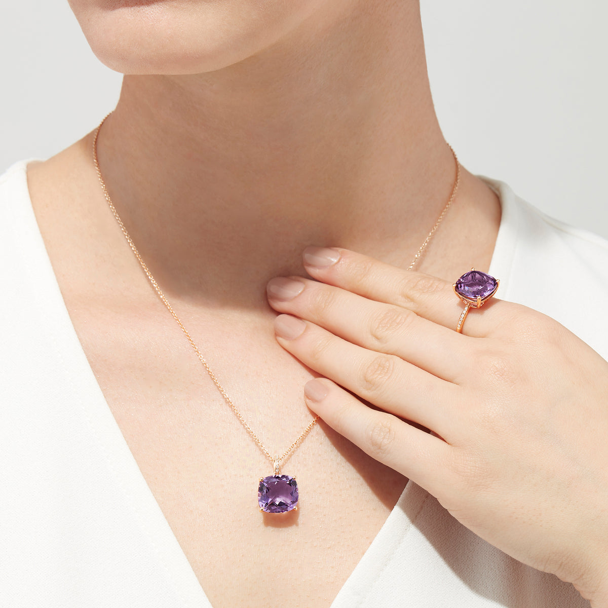The 14K Rose Gold Amethyst and Diamond Pendant, 6.62 TCW, features a cushion-cut amethyst with diamond accents in a four-prong setting and is elegantly displayed on a white background.