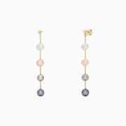 The 14K Yellow Gold Multi Color Cultured Pearl Earrings feature three vertically set cultured pearls in white, pink, and grey-blue hues on a delicate yellow gold chain, shown against a white background.