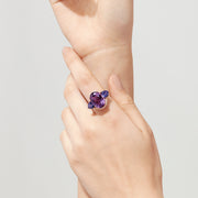 The 14K Rose Gold Amethyst, Tanzanite and Diamond Ring, 10.28 TCW features a striking amethyst center, accented by tanzanites and surrounded by a sparkling diamond halo.