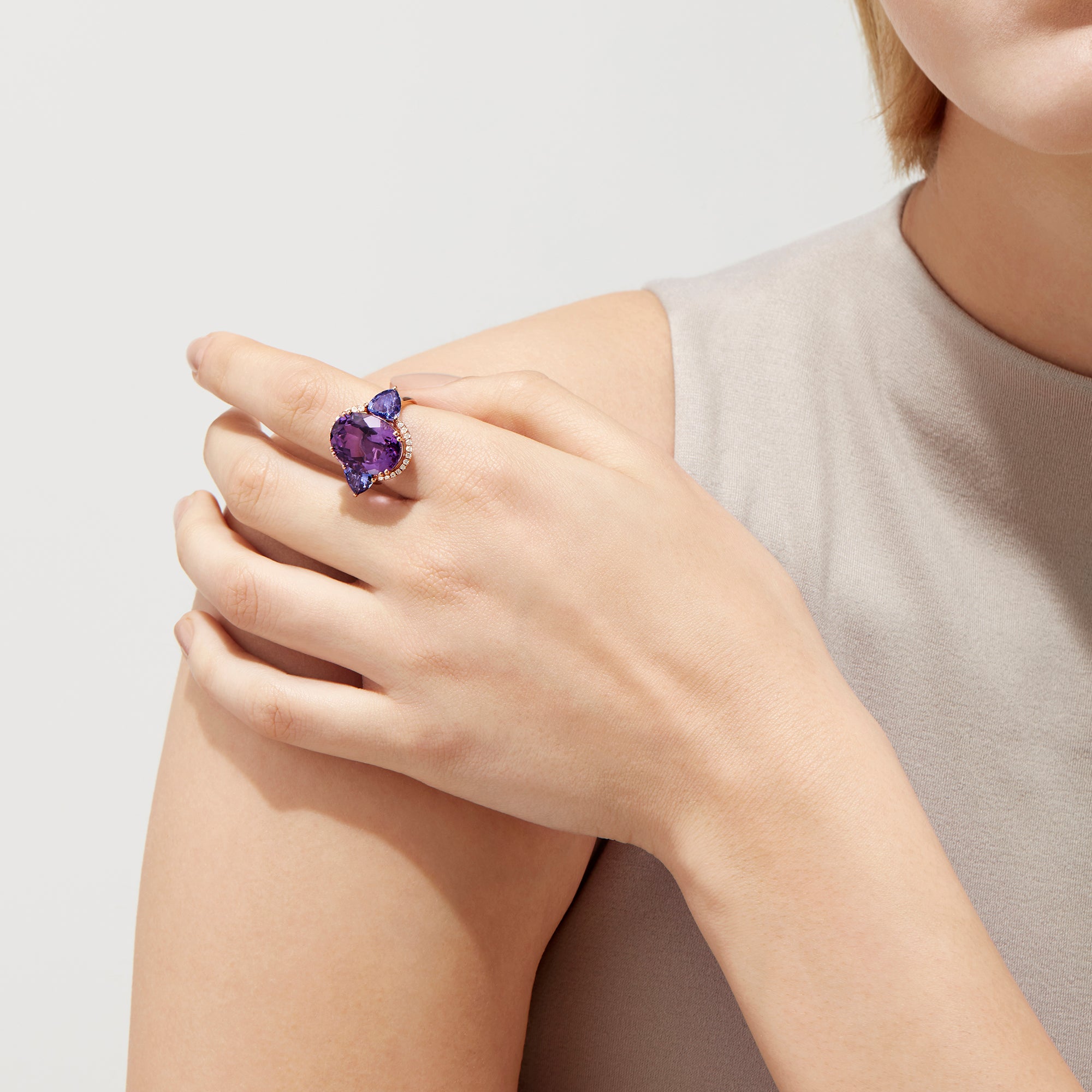 The 14K Rose Gold Amethyst, Tanzanite and Diamond Ring, 10.28 TCW features a striking amethyst center, accented by tanzanites and surrounded by a sparkling diamond halo.