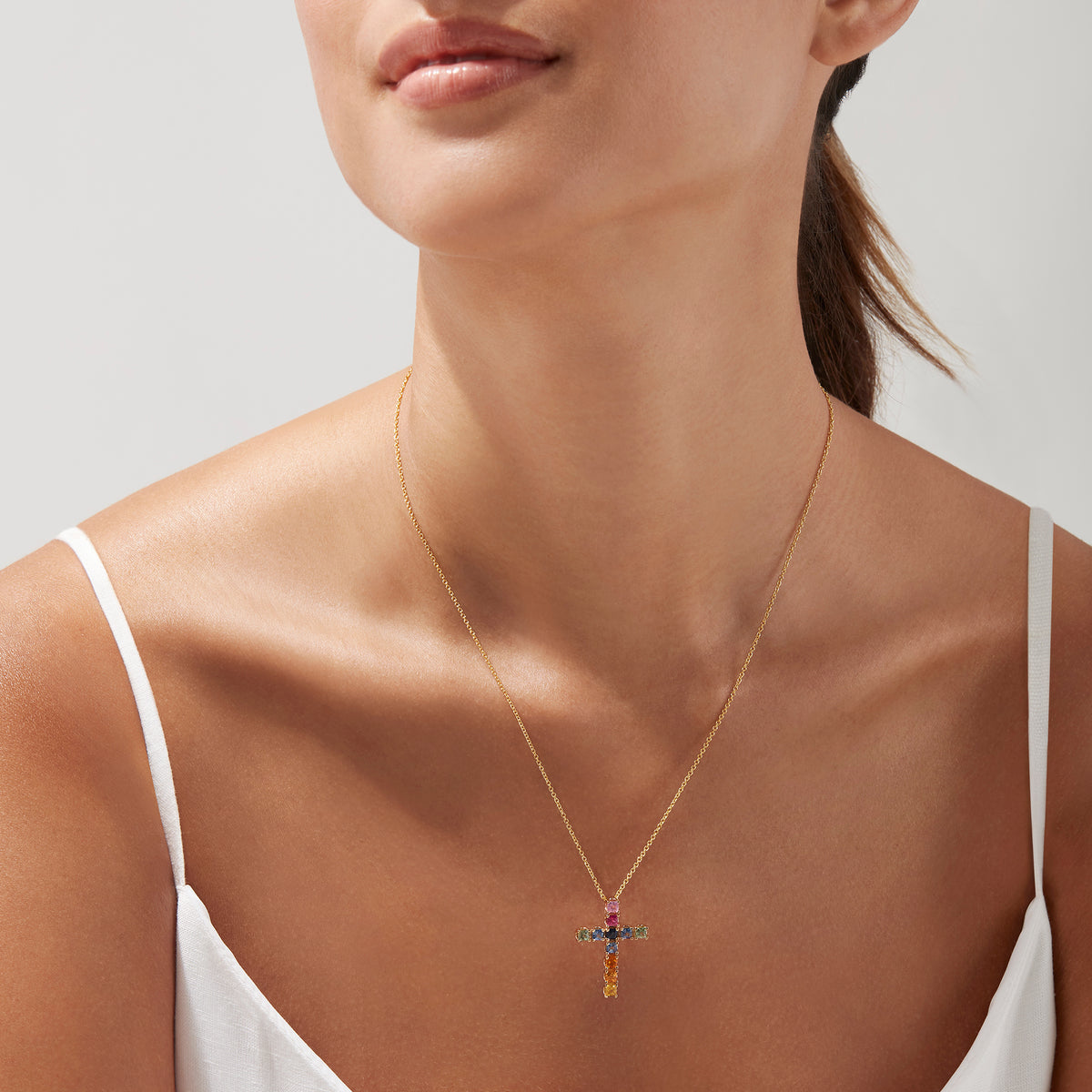 The Watercolors 14K Yellow Gold Multi Sapphire Cross Pendant, 2.05 TCW, showcases vibrant square sapphires in pink, blue, green, orange, and yellow on a stunning yellow gold chain necklace.