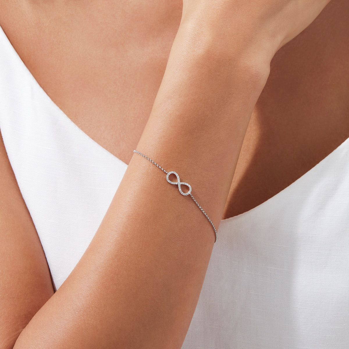 The Novelty 14K White Gold Diamond Infinity Bracelet, 0.12 TCW, features a sparkling infinity symbol on a delicate chain with clasp closure and three adjustable loops for an ideal fit.