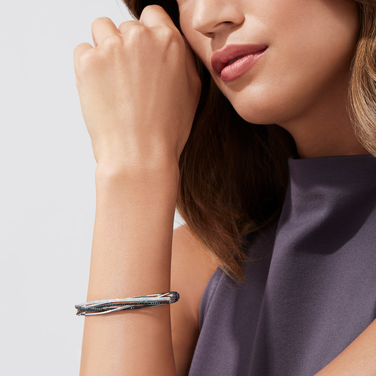 The 14K White Gold Black and White Diamond Bangle, 1.26 TCW, features multiple overlapping bands with sparkling black and white diamonds for a layered, textured look.