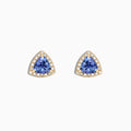 A pair of Nahla Siri 14K Yellow Gold Tanzanite and Diamond Stud Earrings, 1.19 TCW, featuring triangular blue stones surrounded by diamonds, is displayed on a white background.