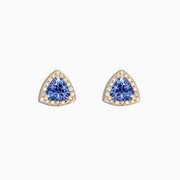 A pair of Nahla Siri 14K Yellow Gold Tanzanite and Diamond Stud Earrings, 1.19 TCW, featuring triangular blue stones surrounded by diamonds, is displayed on a white background.