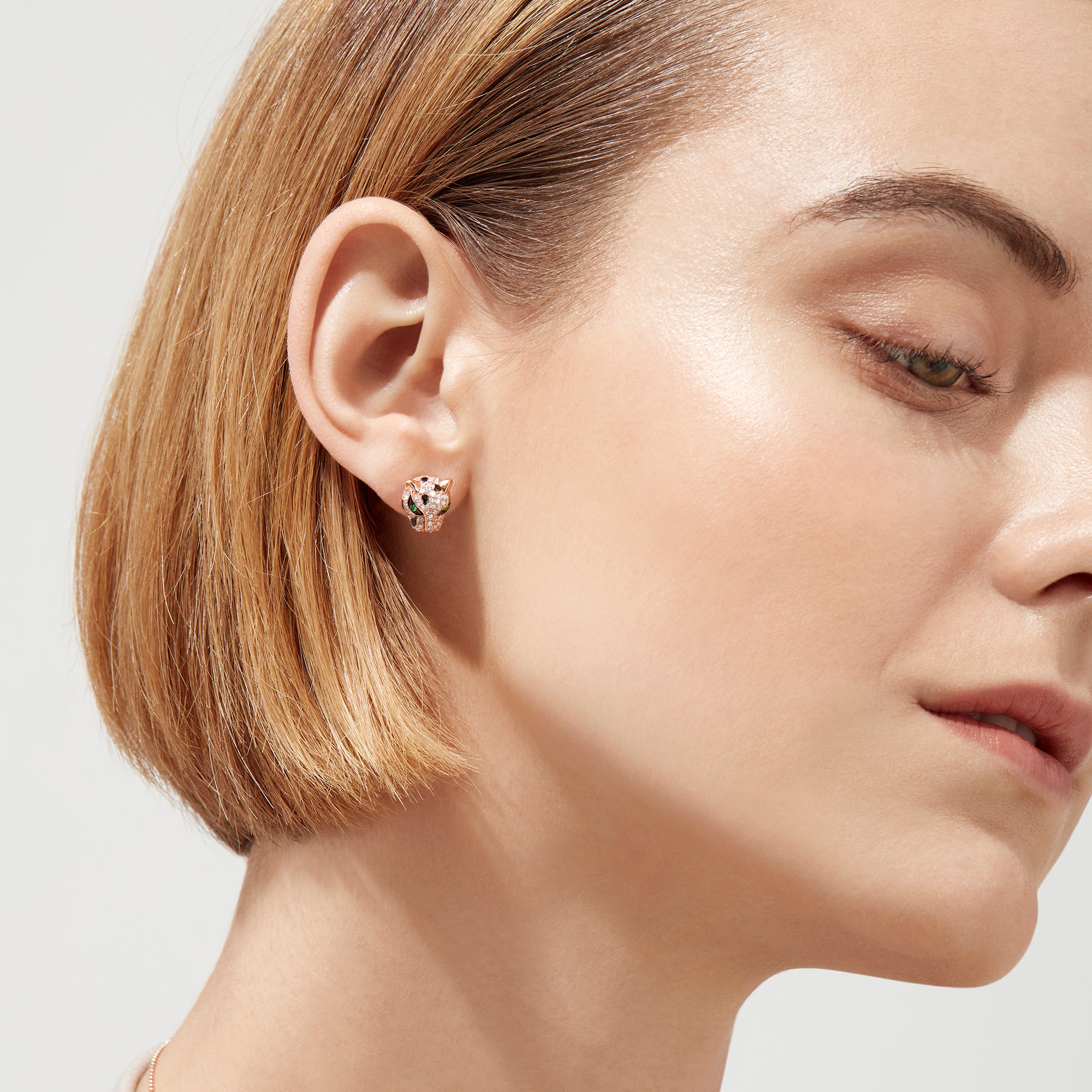 The Signature 14K Rose Gold Diamond and Tsavorite Stud Earrings (0.49 TCW) feature panther-shaped studs with diamond gemstones and vivid green tsavorite eyes, shown on a plain white background.