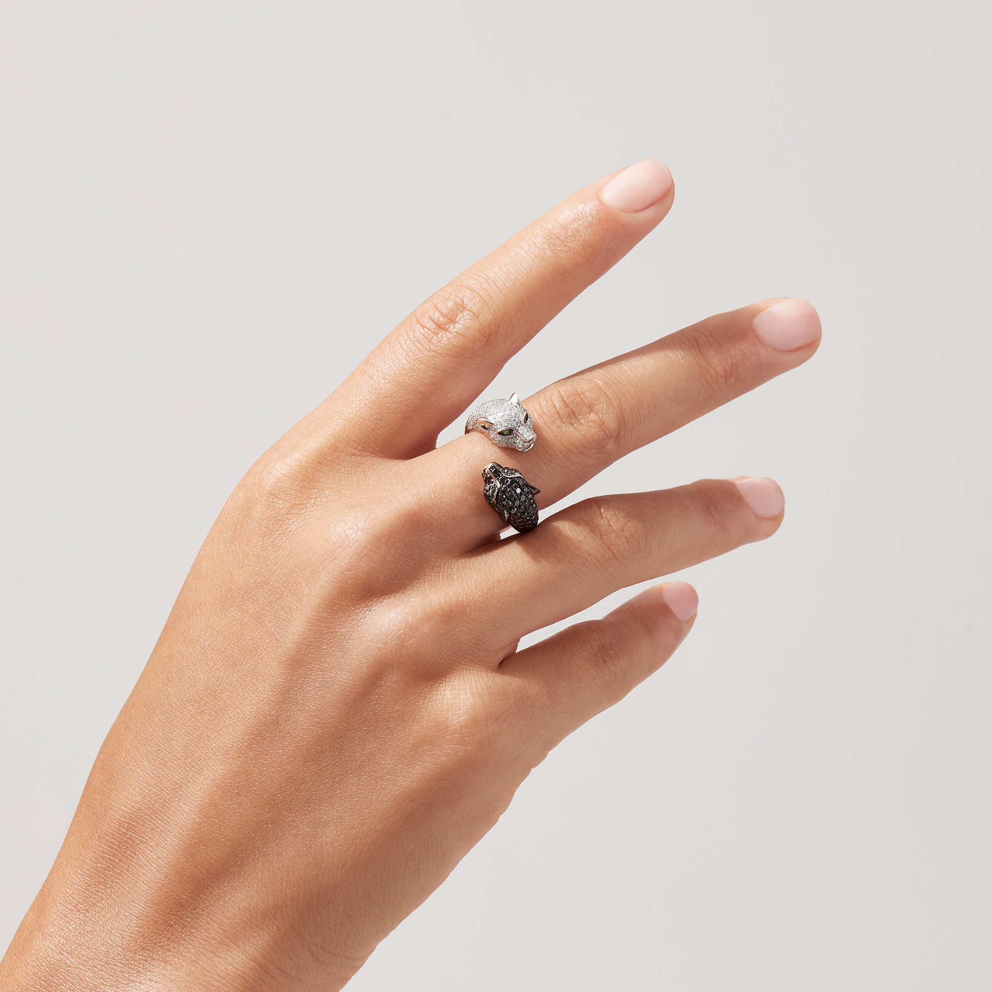 The Signature 14K Gold Black & White Diamond Double Panther Ring, 1.49 TCW, features two panther heads—one with black stones, the other with white—each set with vivid green gemstone eyes.